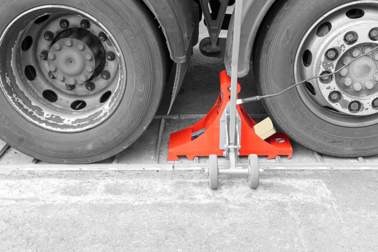 Wheel chock POWERCHOCK 9 set up in front of truck wheel on ground plate